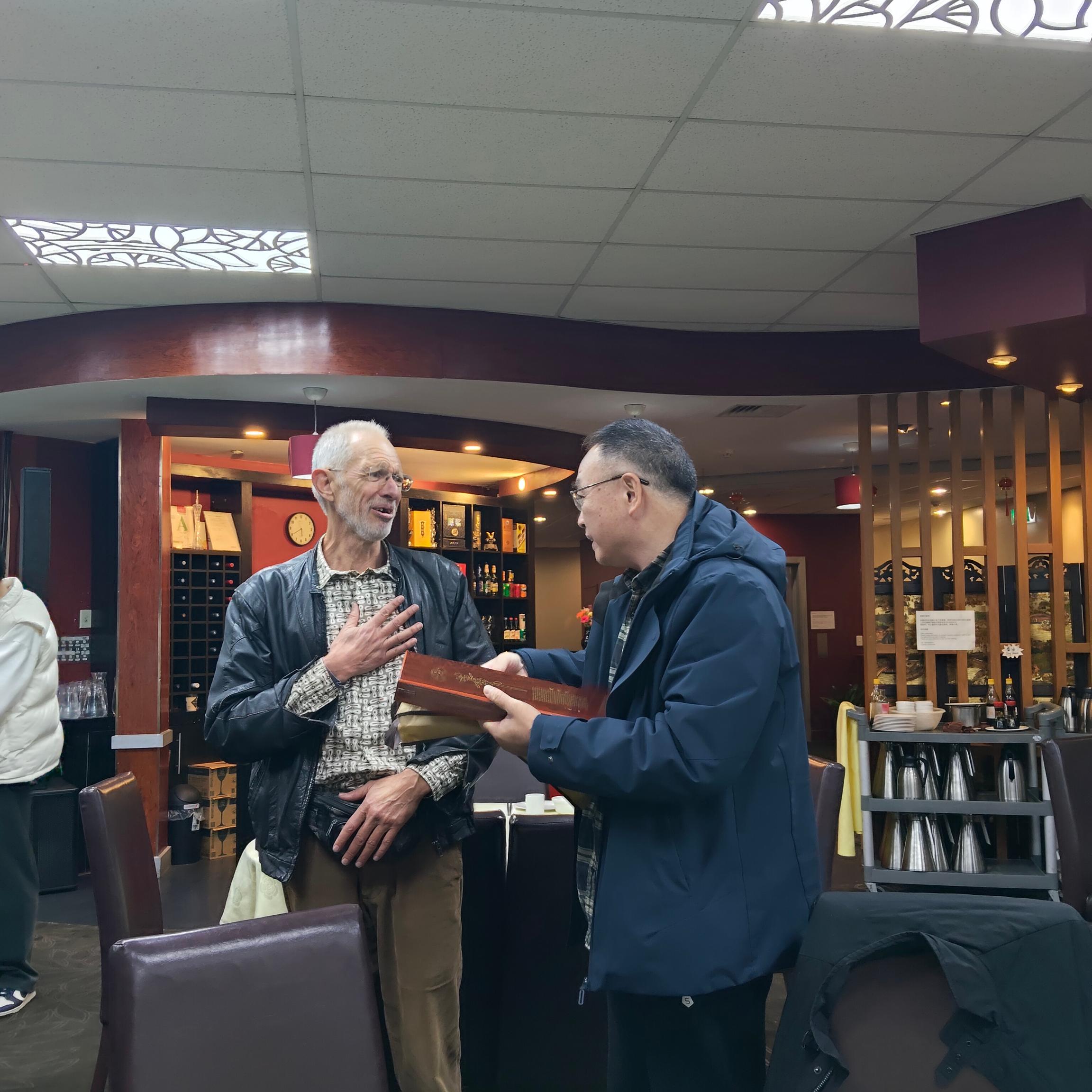 Chinese giving gift to Māori person