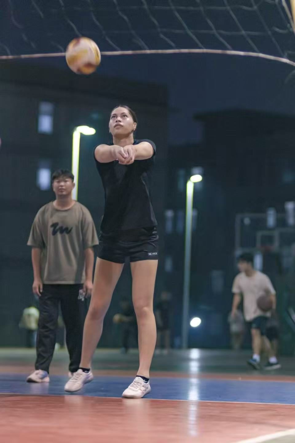 A volunteer playing netball on an outdoor court in China