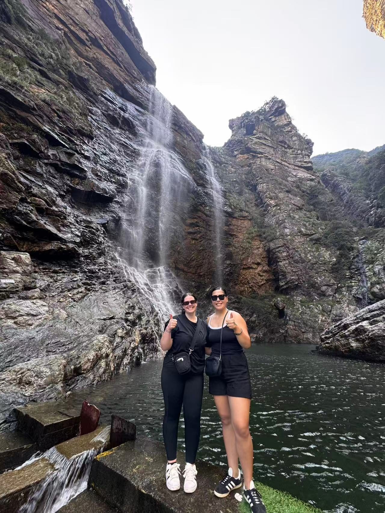 Two volunteers in front of a waterfall during a weekend trip