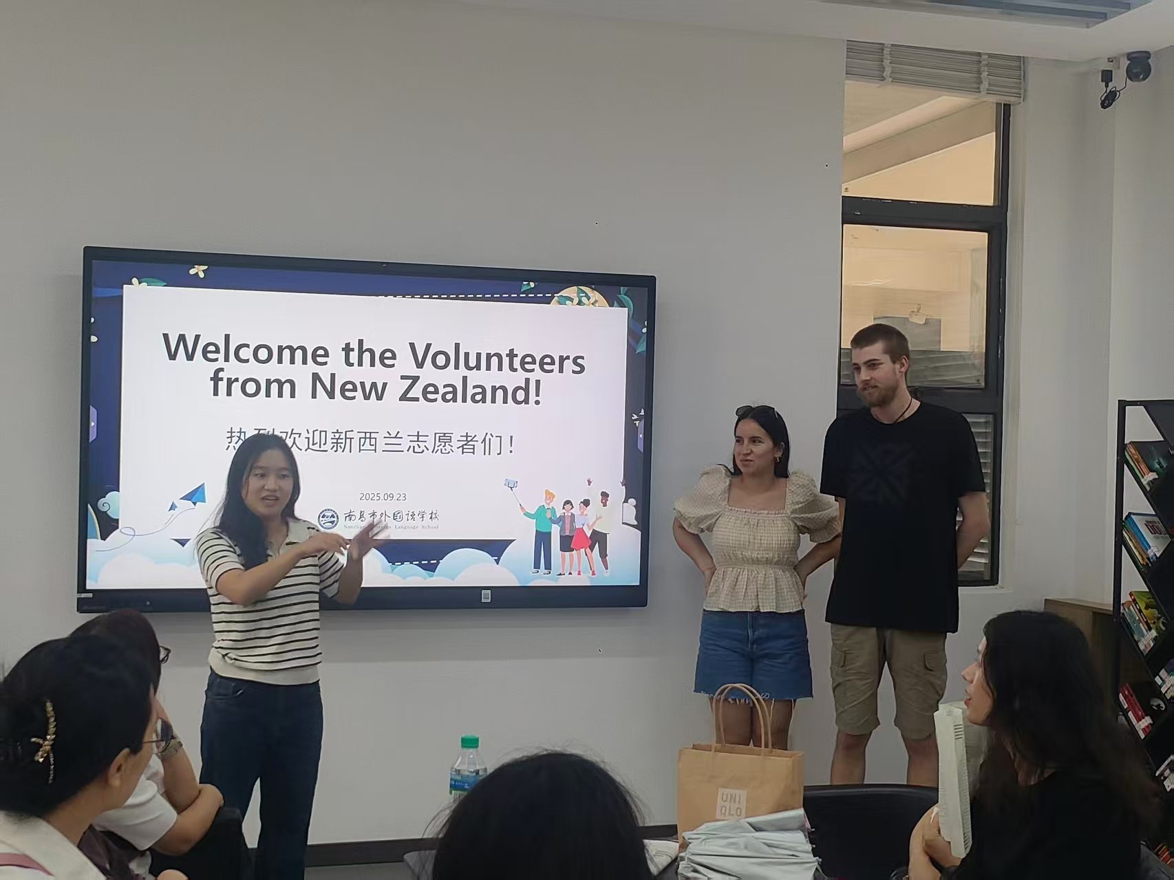 Volunteers at a welcome event, under a screen reading Welcome the Volunteers from New Zealand