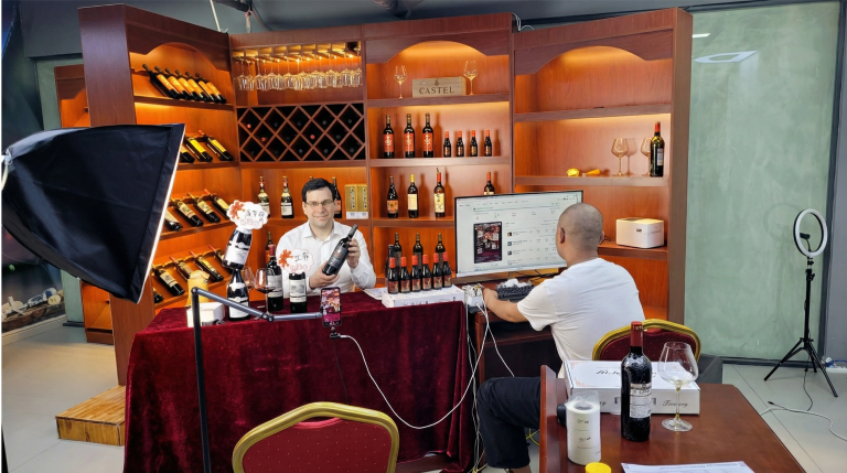 A livestream presenter promoting wine in front of shelves of bottles